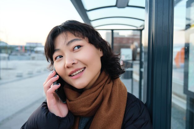 冬に立っている電話で話していると笑顔で電話をかけるかわいい韓国人女性のクローズアップ