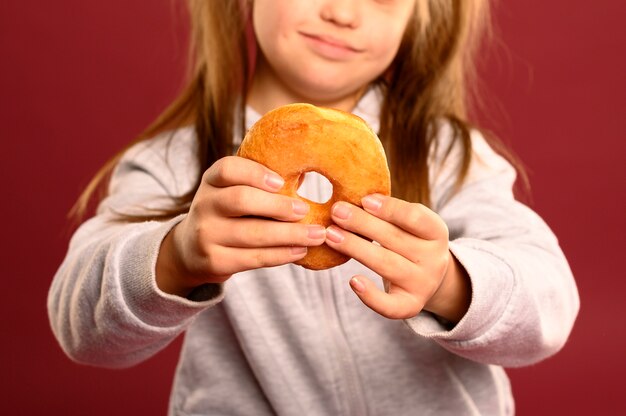 Макро милая молодая девушка держит пончик