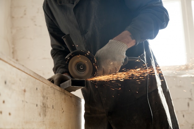 Close up of cutting metal pipe, man using angle grinder