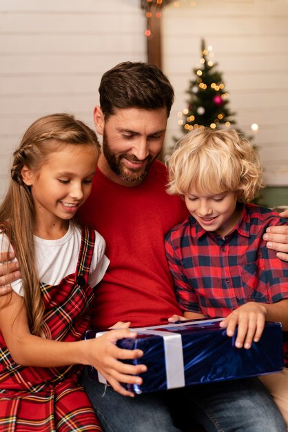 Close up on dad and kids opening gifts