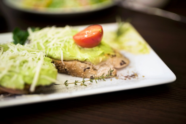 Close-up of delicious bread with pesto sauce and cherry tomato on plate