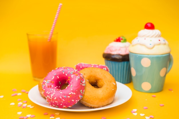 Close-up of delicious donuts and muffins on yellow background