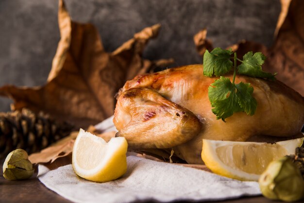 Close-up of a delicious roasted chicken with lemon slice on table cloth