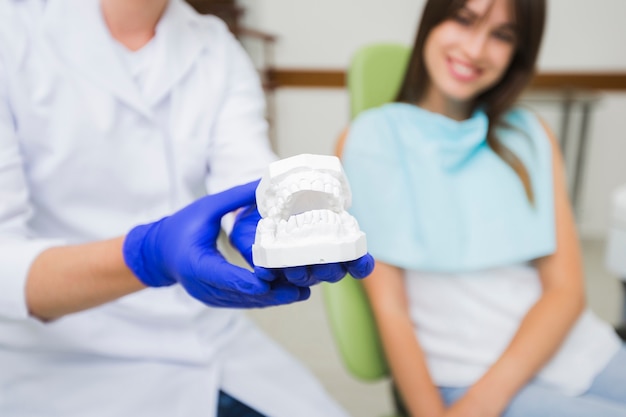 Close-up of dentist holding dentures with patient