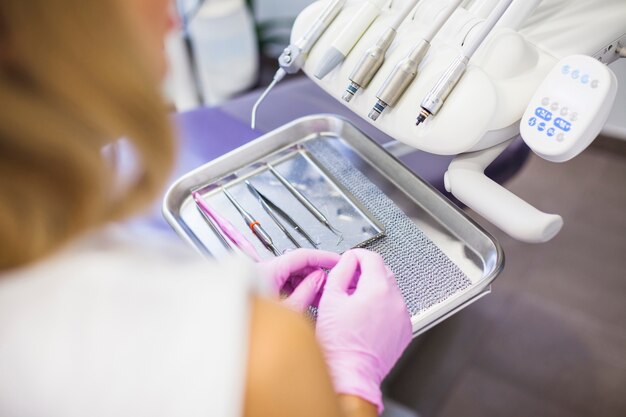 Close-up of a dentist placing dental tools on tray