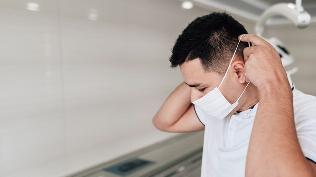 Close-up of dentist putting on surgical mask