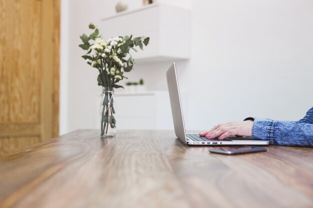 Close-up of desk with businesswoman working and vase