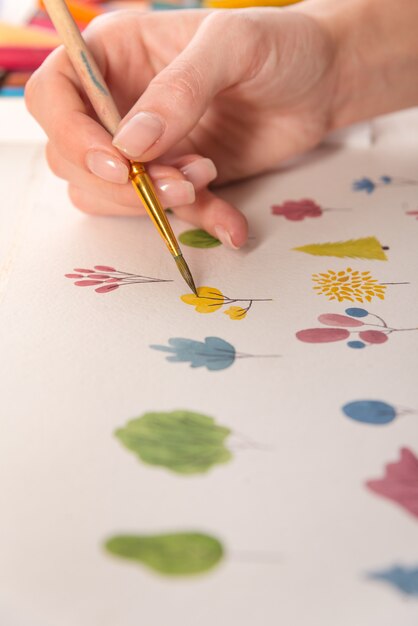 ブラシと水彩絵の具で紙に描かれた色とりどりの花の自然デザインのクローズアップ