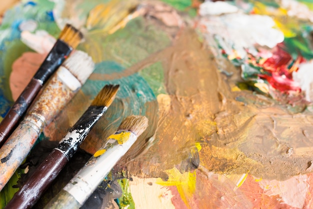 Close-up of dirty paintbrushes over oil painted surface