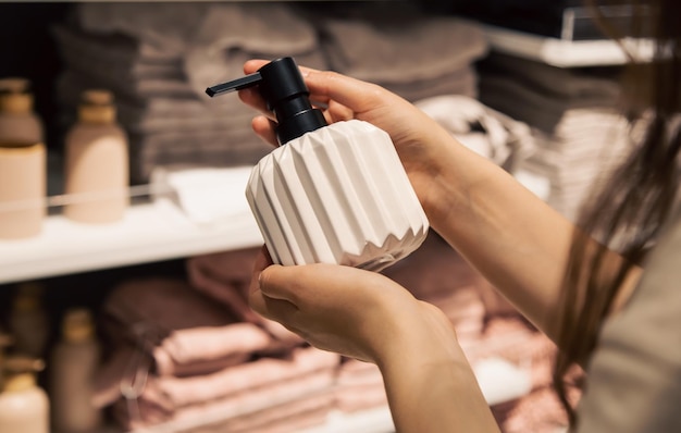 Close up a dispenser for liquid soap in female hands in the store