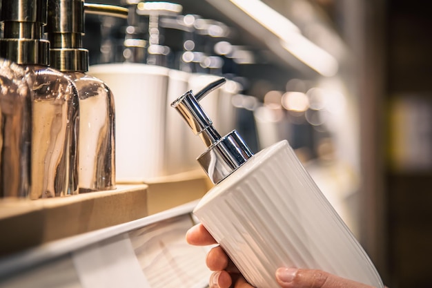 Close up a dispenser for liquid soap in female hands in the store