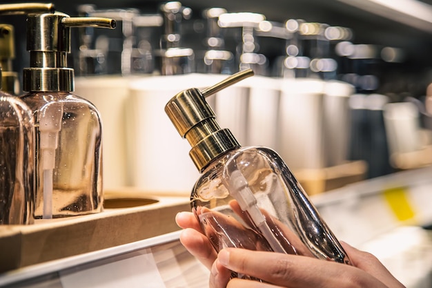 Free photo close up a dispenser for liquid soap in female hands in the store