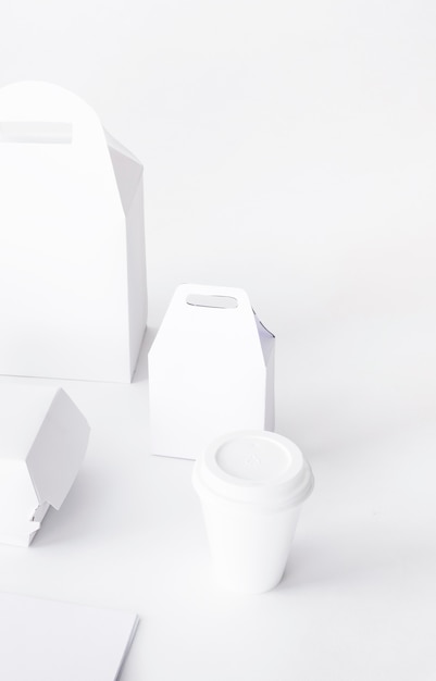 Free photo close-up of disposal cup and food parcel mock up on white background