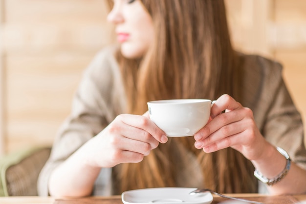 Close-up of distracted woman with cup of tea