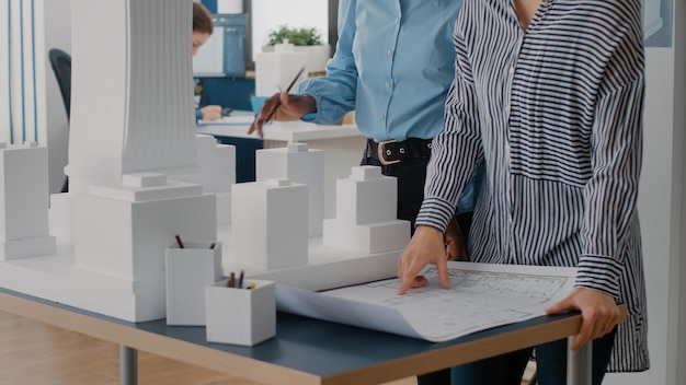 Close up of diverse team of women working on blueprints design in office. Multi ethnic architects using industrial print on table to plan construction layout for architecture project.