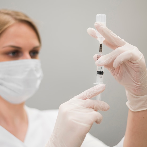 Close-up doctor filling syringe