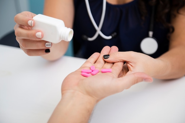 Close-up doctor giving pink pills