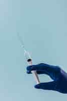 Free photo close-up of a doctor hand with syringe on blue backdrop