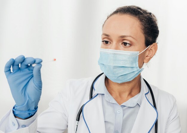 Close-up doctor holding cotton swab