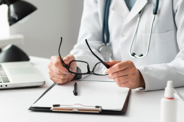 Close-up doctor holding eyeglasses