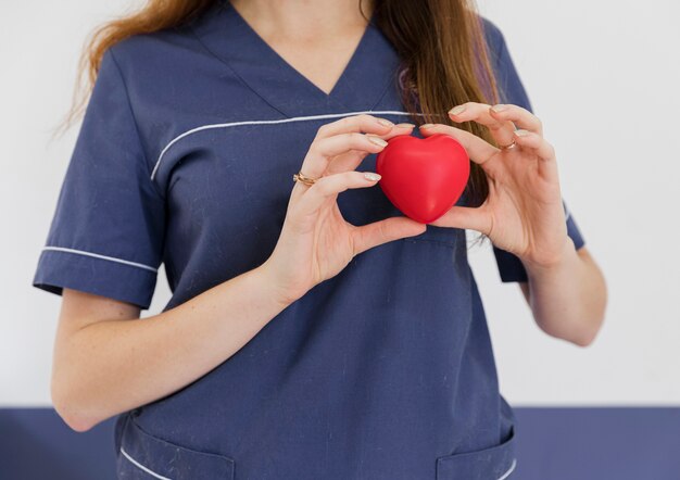 Close-up doctor holding heart shaped toy