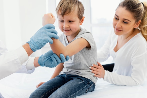 Foto gratuita medico del primo piano che tiene il braccio del bambino