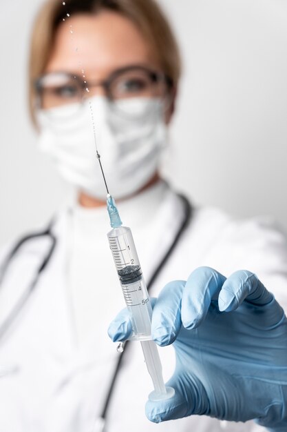 Close-up doctor holding medical syringe