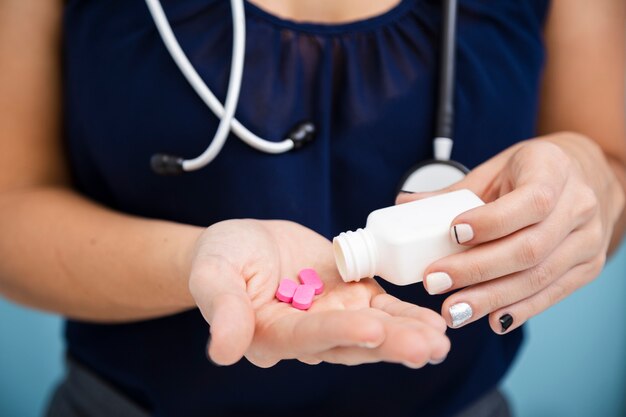 Close-up doctor holding pink pills