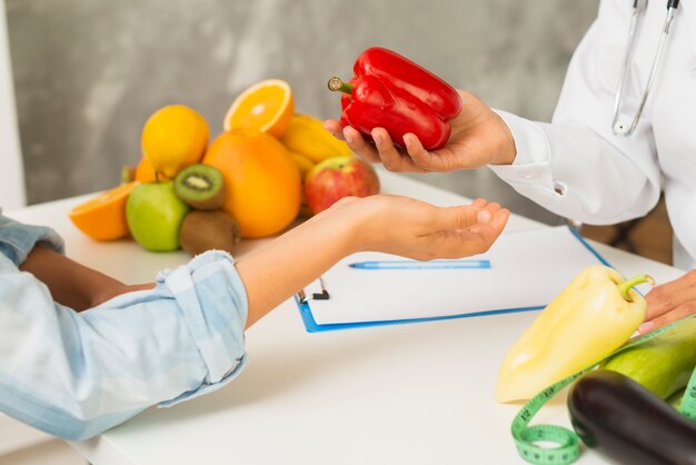 Close-up doctor and patient with red bell pepper