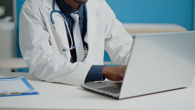 Close up of doctor typing on laptop keyboard in medical cabinet