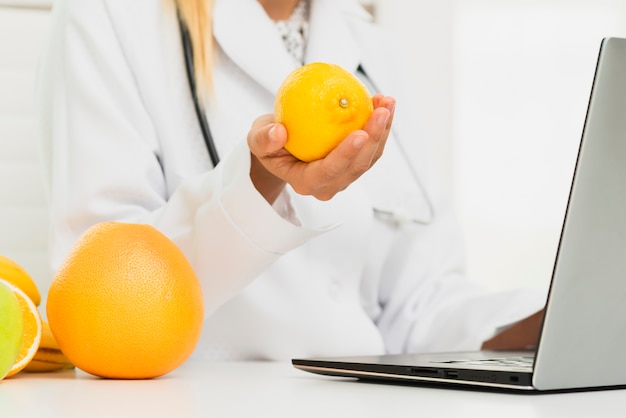 Free photo close-up doctor with lemon and laptop