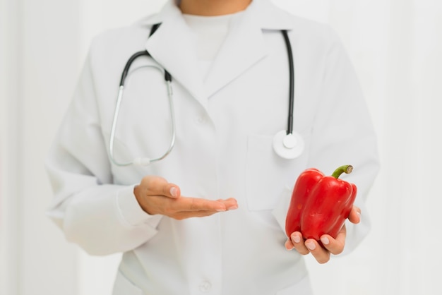 Close-up doctor with stethoscope and bell pepper