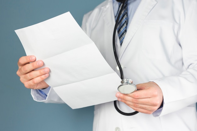 Free photo close-up of doctor with stethoscope holding medical report in hand