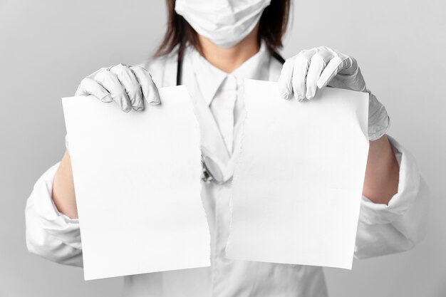 Close-up doctor with surgical mask holding papers