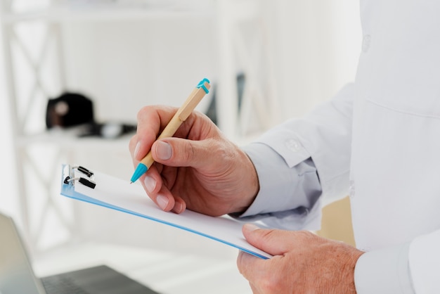 Close-up of doctor writing on clipboard