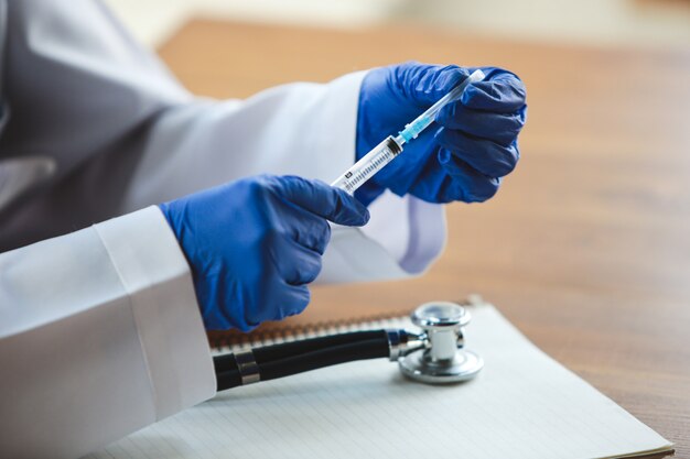 Close up of doctors hands with stethoscope, sheets and pills on wooden background