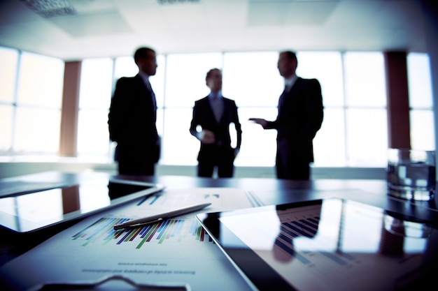 Close-up of documents with businessmen blurred background