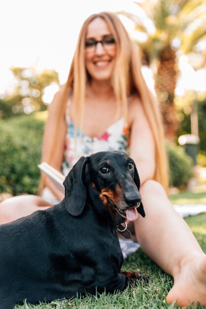 Close-up of a dog in front o smiling young woman