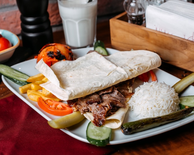 Close up of doner meat with french fries rice and vegetables on plate