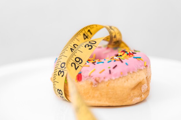 Close up of donut and measuring tape weight loss and diet concept