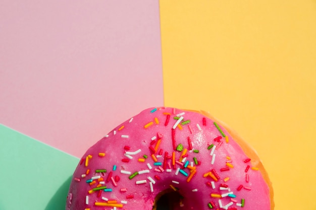 Close-up of donut with sprinkles against yellow; pink; and mint green backdrop