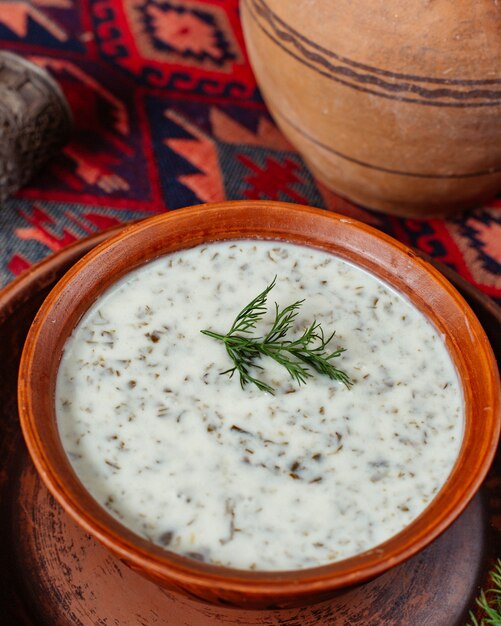 Close up of dovga herbs soup place on traditional carpet