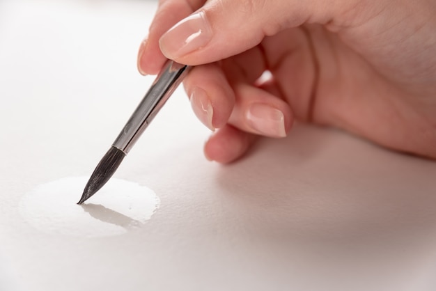 Крупным планом процесса рисования кистью на белой бумаге