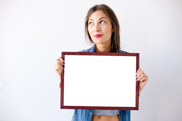 Close-up dreaming girl with a blank white placard or poster