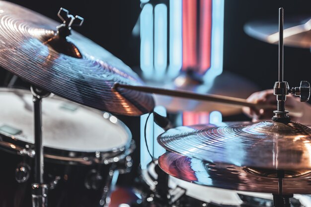 Close-up of drum cymbals as the drummer plays with beautiful lighting on a blurred background.