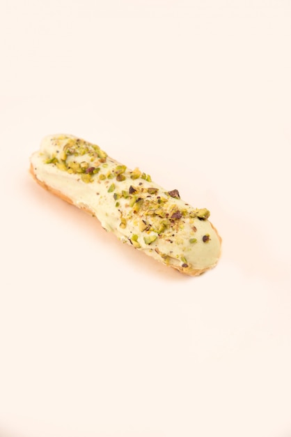 Close up of eclair with white cream and nuts isolated over white