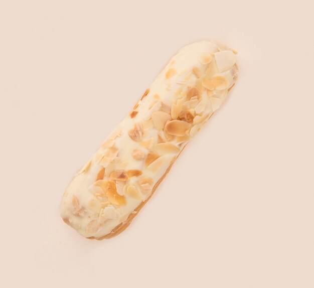 Close up of eclair with white cream and nuts isolated over white