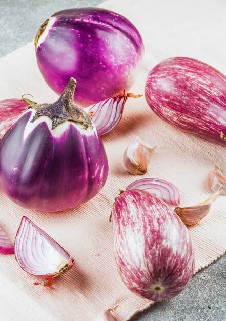 Close-up of eggplants; garlic cloves and onions on cloth