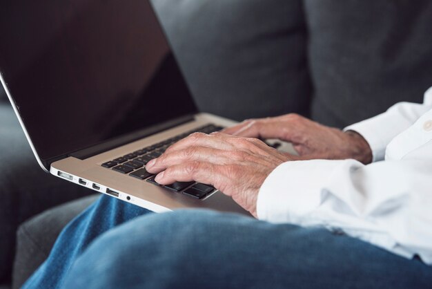 Close-up of an elderly man's hand typing on laptop