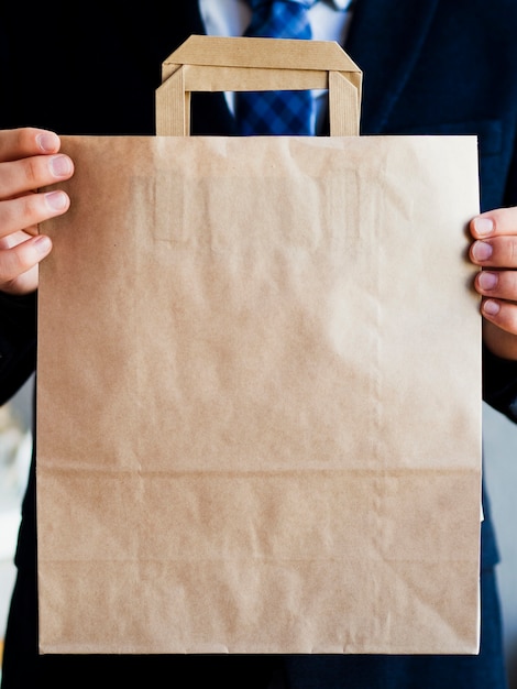 Close-up elegant man holding up paper bag